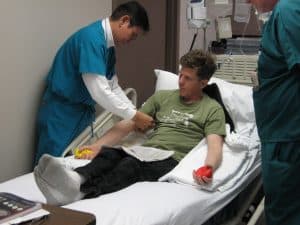 Steve in hospital bed, arm being tied off.