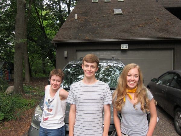 Triplets, posing in front of a packed van, ready to leave for college. 